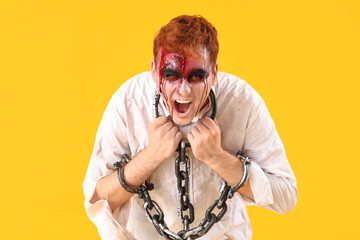 Scary zombie man with chains on yellow background