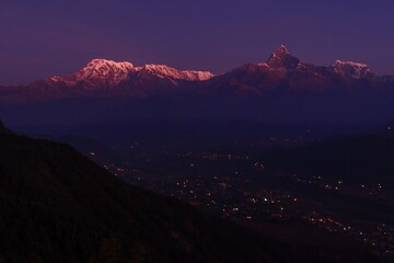 Annapurna and Machapuchare in purplish dawn light, overlooking glittering Pokhara from Sarangkot.
