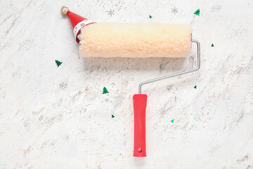 Paint roller with Santa hat and confetti on white background