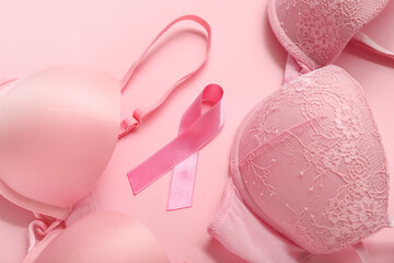 Pink ribbon with bras on color background, closeup. Breast cancer awareness concept