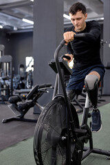 Fototapeta na wymiar active man concentrated on working out on a stationary bike. A man is engaged in sports in the gym. full length shot. motivation, strength training