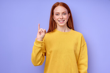 beautiful redhead happy cheerful girl, teacher showing letter J on blue background. Sign language...