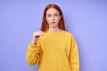 beautiful redhead serious girl, teacher showing letter T on blue background. Sign language alphabet. free education for deaf children