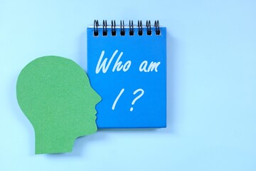 Who am I question in blue notebook. Self awareness and knowledge concept.