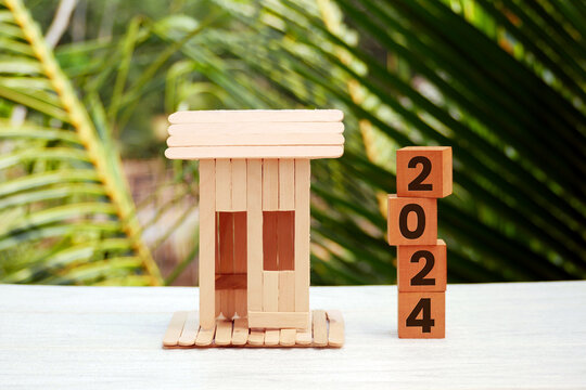 Miniature houses and wooden blocks number 2024 are used as concepts for saving money buying a house, New Year property, business, real estate, and property concepts.