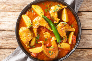 Authentic Bengali fish curry with potato closeup on the plate on the wooden table. Horizontal top view from above