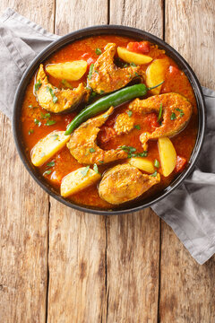 Pabda macher jhol Bengal fish Dish closeup on the plate on the wooden table. Vertical top view from above