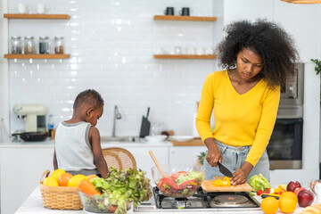 Portrait of enjoy happy love african american family mother and african little boy son child having fun help cooking food healthy eat together with fresh vegetable salad and ingredient in kitchen