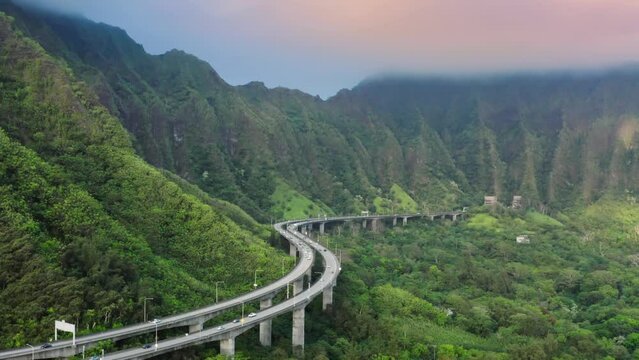 Interstate H3 passing through majestic green Koolau Mountains with Trans-Koolau twin tunnels.Aerial along highway with epic nature landscape views. Scenic route on Oahu Hawaii island at golden sunrise