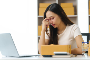 Fail and stress Asian businesswoman, visibly strained, navigates the rush of packing products, each...