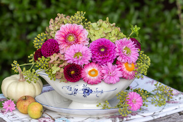 romantisches Blumengesteck mit pink Dahlien, Astern, Hortensienblüten und Strohblumen in Sauciere