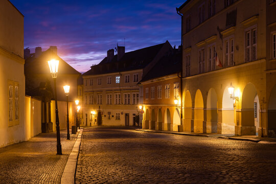 Quiet street of Prague, the capital of Czech Republic. Empty cobblestone road lit by vintage lamps under the colorful sky just before daybreak.