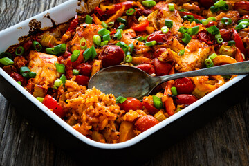 Jambalaya one pot dish - fried chicken breasts with white rice, tomatoes, bell pepper and celery on wooden table
