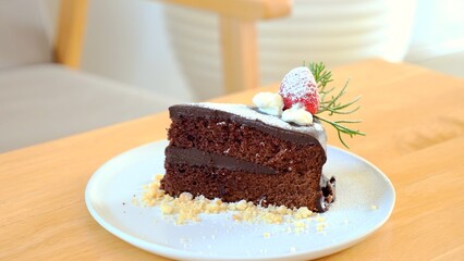 Sliced chocolate brownie on white plate, garnished with strawberry. Close-up of delicious dessert with rich chocolate flavor and creamy texture.