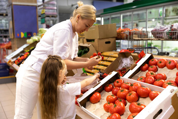 Shopping with kids. Mother and child buying fruit in supermarket. Mom and little girl buy fresh...