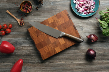 Top view of cutting board and beautiful chef knife. H chopped onions and other fresh vegetables in the home kitchen. Preparing a salad of fresh vegetables.