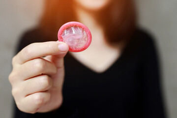Condom ready to use in female hand, give condom safe sex concept on the bed Prevent infection and Contraceptives control the birth rate or safe prophylactic. World AIDS Day, Leave space for text.