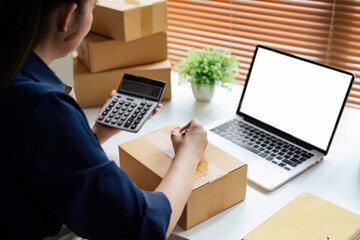 Young woman online business owner is preparing a parcel box to prepare the package for delivery to...