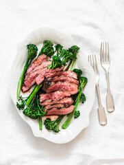Grilled beef steak and broccolini - delicious lunch, appetizer, tapas on a light background, top view