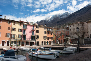 Small hotels in a mountain resort. In the foreground is a pier with pleasure boats