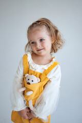little girl in a yellow dress on a white background makes emotions