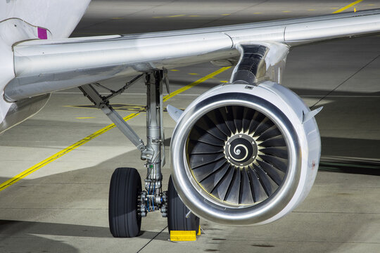 Closeup of jet engine, main gear and wing of passenger airplane parked on the apron at an airport at night