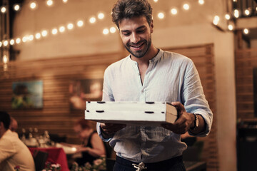 Evening Takeout: Man with Pizzas Exiting Pizzeria - Man in his 30s leaves a pizzeria at night with...