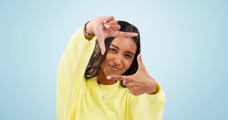 Hands, frame and face of woman in studio with trendy outfit, fashion style and casual clothes. Perspective, happy and portrait of indian person with finger shape for photography on blue background