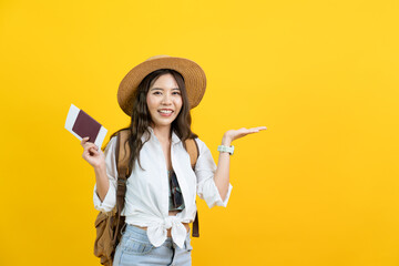 portrait of young Asian woman traveling abroad showing passport open hand isolated yellow studio...