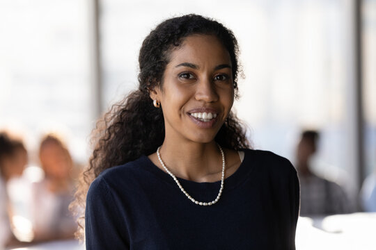 Head shot portrait smiling successful African American businesswoman in office, confident happy young woman entrepreneur employee executive worker looking at camera, posing for corporate photo