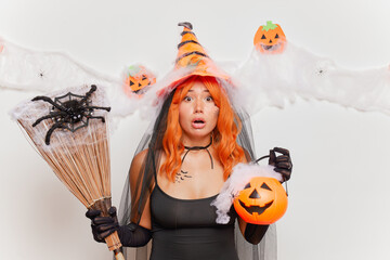 Surprised young woman in halloween costume looking at camera isolated over white background