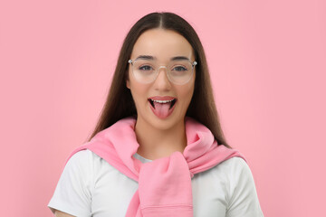 Happy woman showing her tongue on pink background