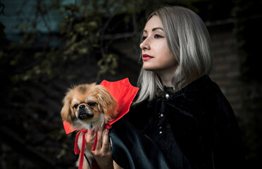 Woman with a nice pet in masquerade vampire Halloween costume. Concept of party