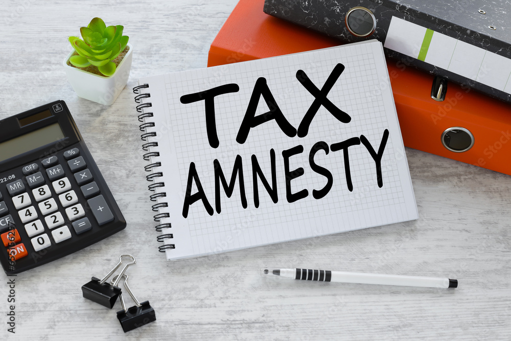 Poster orange folder and calculator. tax amnesty wooden background stickers on open notepad with text