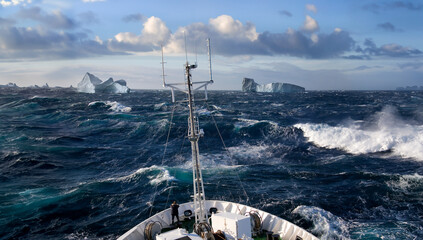 Ship rolling in heavy seas near icebergs in Scoresbysund on the east coast of Greenland.