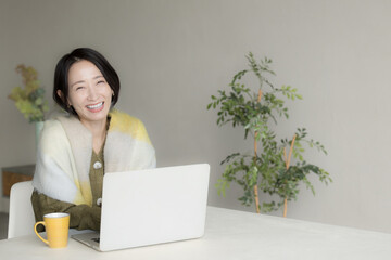 A woman who looks like a housewife or mother in winter clothes operating a laptop