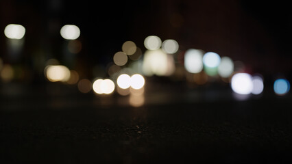 Low angle bokeh background of night city with car light passing by - obrazy, fototapety, plakaty