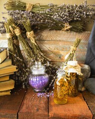 Vintage books, dried lavender flowers and bottles of essential oil on wooden background.