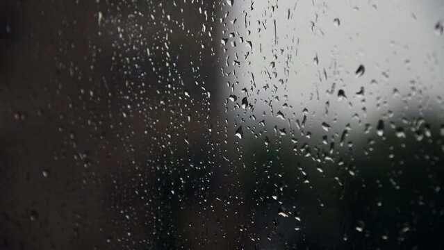 Abstract rainy background. Few raindrops runs down apartment window. Dark blurred city buildings in the background. Soft focus. Time lapse video. Bad weather forecast theme.