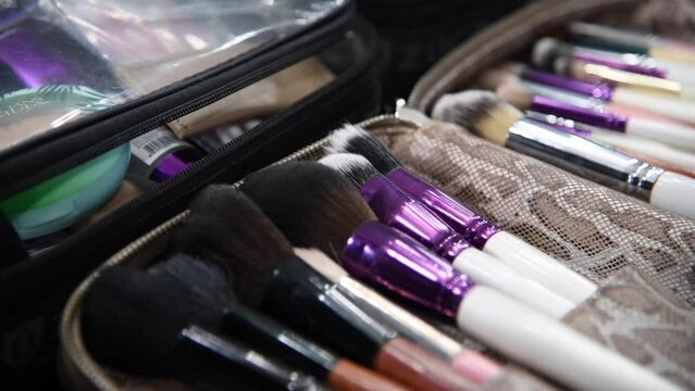 Close-up view of various profeccional make-up brushes lying in case on table in beauty salon. Real time video. Cosmetic tools theme.