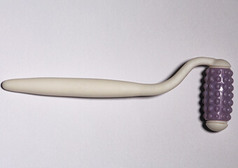 The white tool that is used for a facial massage in cosmetic medicine.