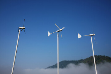 Fototapeta premium Vintage Windmills airplane shape for electric power production with foggy and blue sky on the hill and mountain