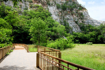 Fototapeta na wymiar ฺBeautiful walkway wooden bridge for lake with rocky mountain view at Khao ngoo national park, Ratchaburi, Thailand