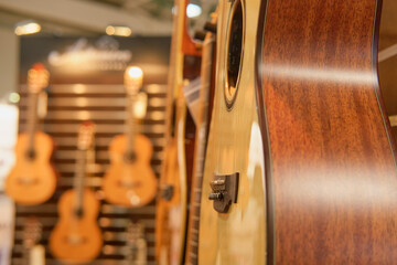 Acoustic guitar in music store, note shallow depth of field. - obrazy, fototapety, plakaty