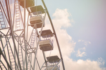 Ferris wheel against the blue sky with white clouds close-up