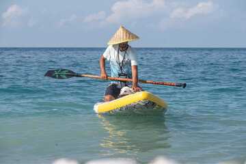 a guy on a sup board with a paddle with a dog stands on the sea in summer