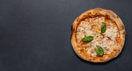 Margherita pizza with basil leaves on black background with copy space. Mozzarella and tomato sauce...