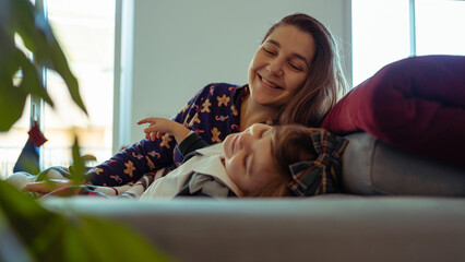 Loving single mother and her daughter bonding sitting on the sofa at home, single life