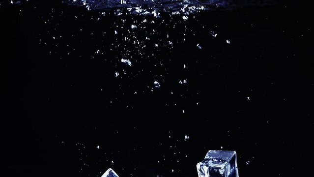 4x slow motion of ice cubes placed in water with air bubbles on black background, refreshing.