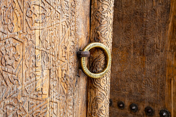 A beautiful ring can be seen on the handle outside the beautifully carved door - obrazy, fototapety, plakaty